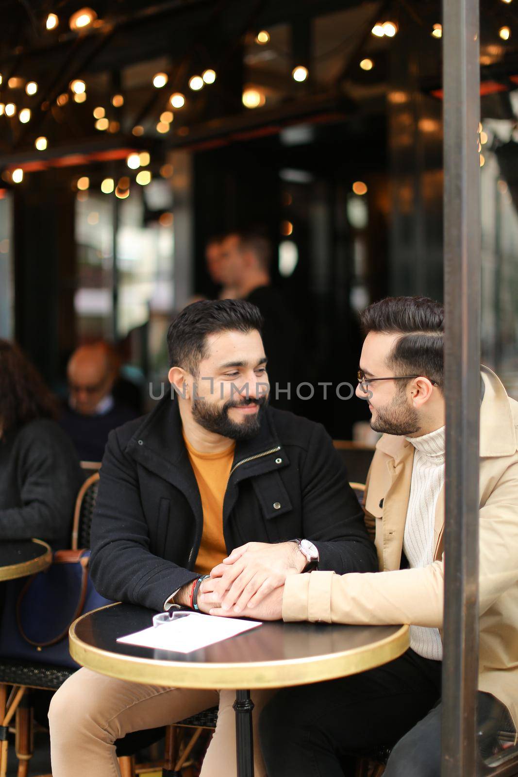 Two american gays talking at street cafe and holding hands. Concept of same sex couple and lgbt.