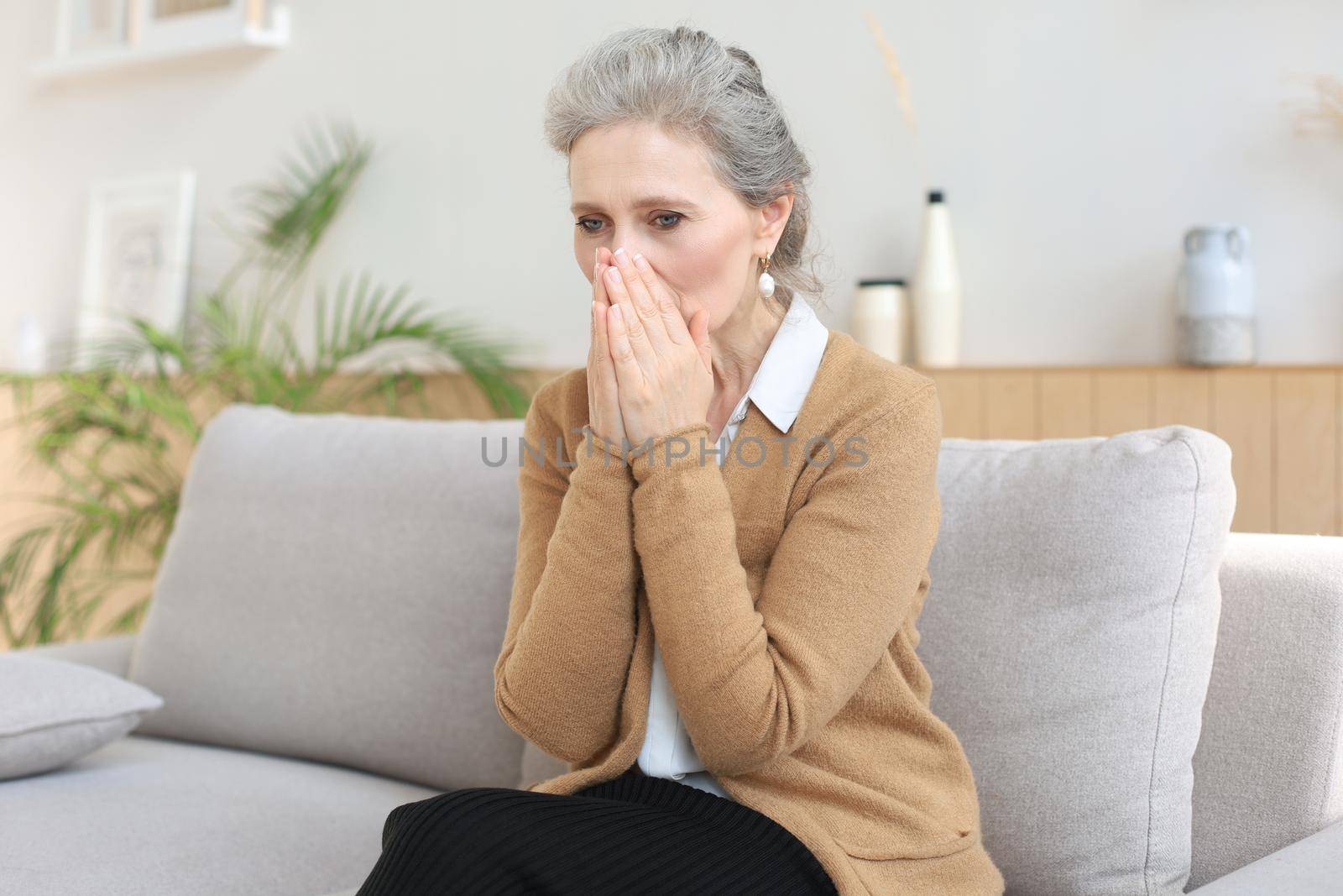 Worried middle aged woman sitting on a sofa in the living room