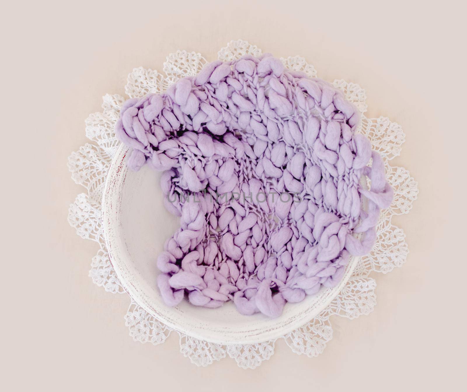 Beautiful backdrop for newborn photosession with flowers hydrangea. Digital composite with basin filled with knitted blanket isolated on light pink background. Top view