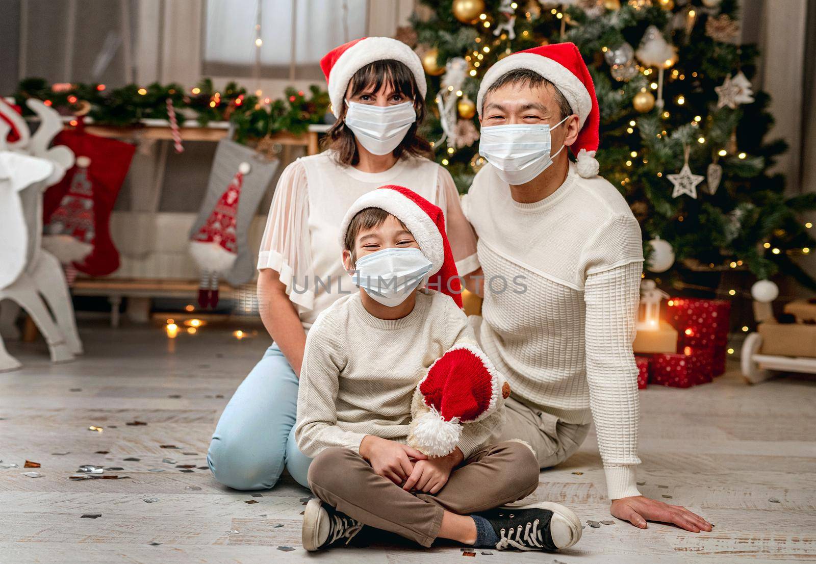 Happy family in protective masks celebrating christmas by tan4ikk1