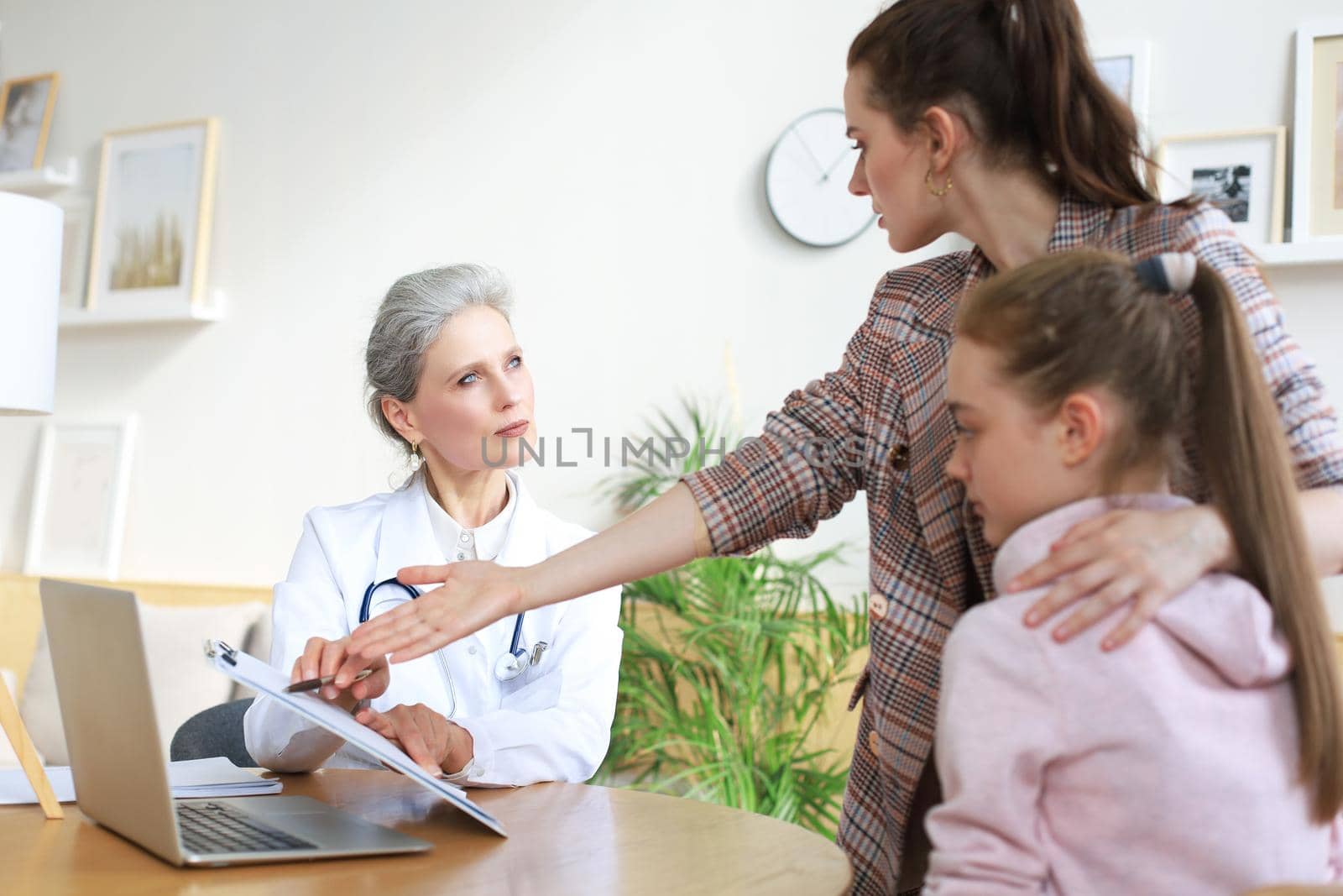 Mother and child in the doctor office meeting the pediatrician, they are sitting at desk in hospital
