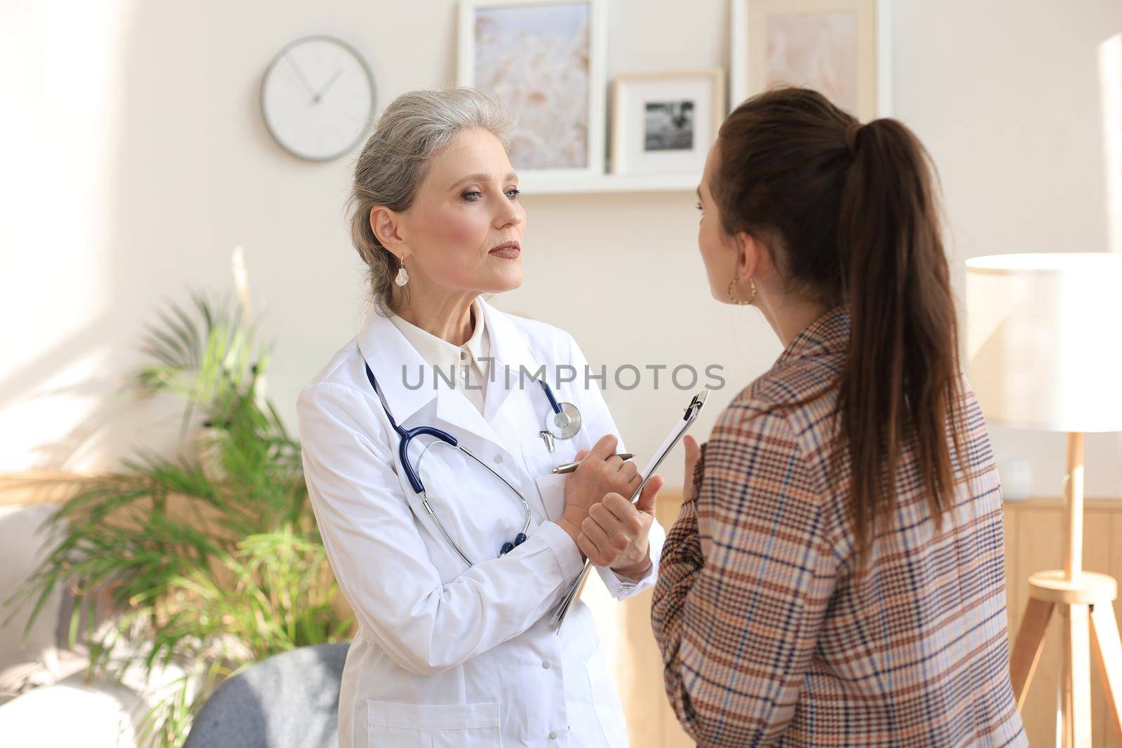 Friendly middle aged female doctor encouraging, supporting patient after medical examination
