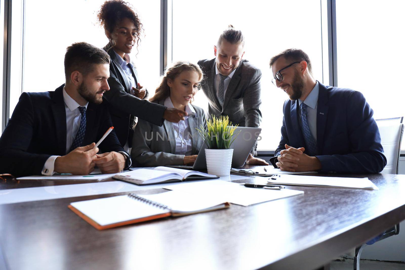 Group of young modern people in formalwear smiling and discussing something while working in the modern office.