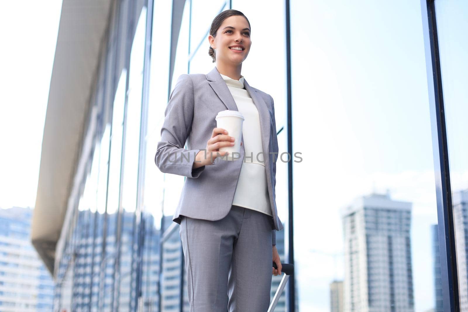 Portrait of successful business woman traveling with case at airport. Beautiful stylish female travel with luggage