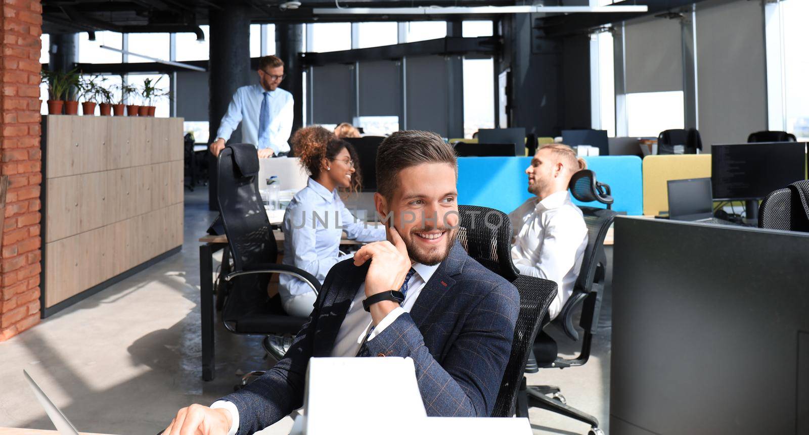 Businessman with colleagues in the background in modern office.