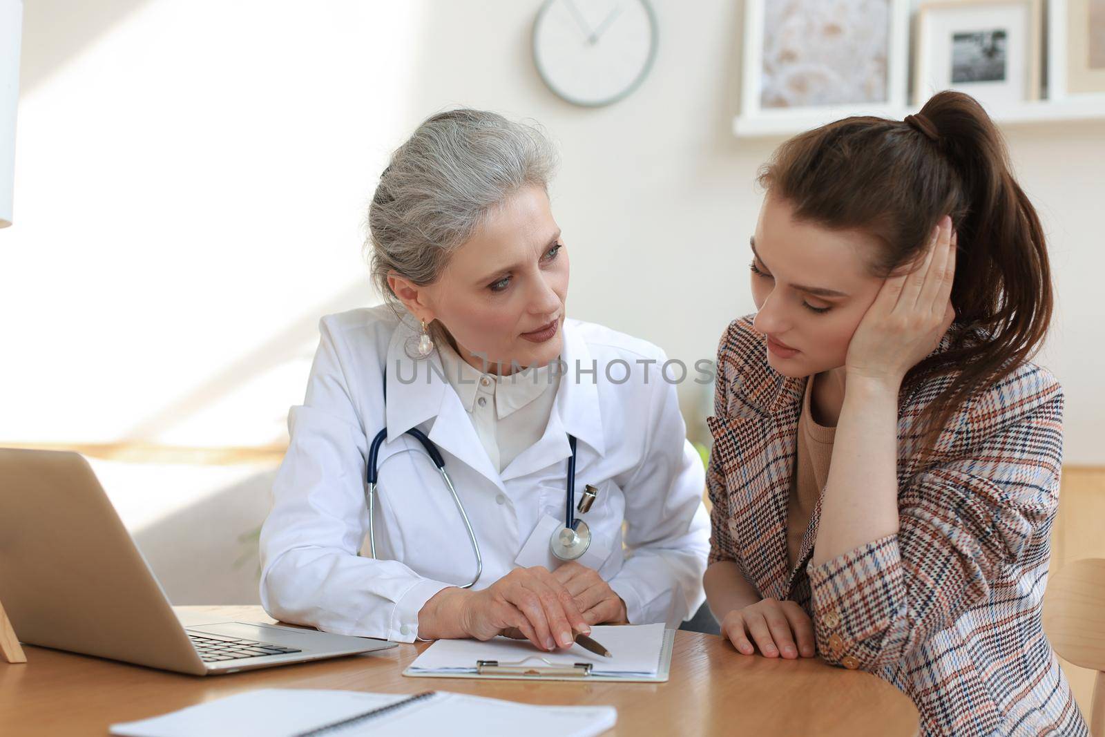 Middle aged female doctor therapist in consultation with patient in office