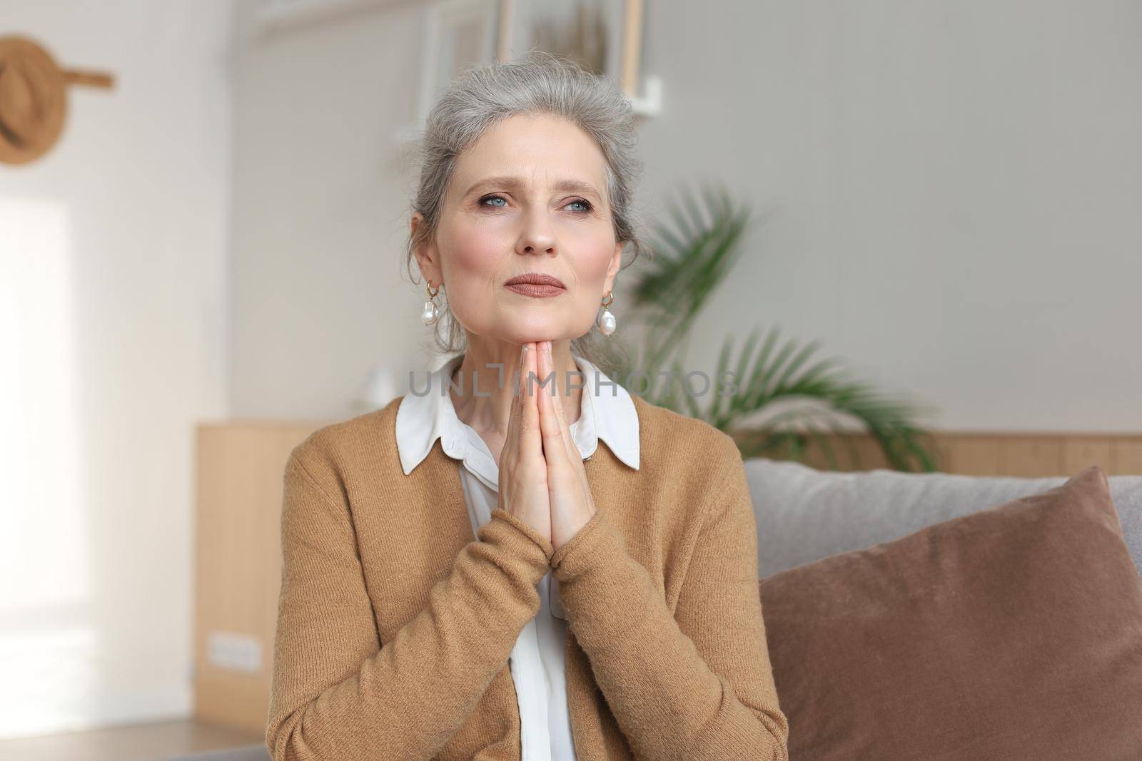 Middle aged woman praying, eyes opened, looking up, hoping for best, asking for forgiveness