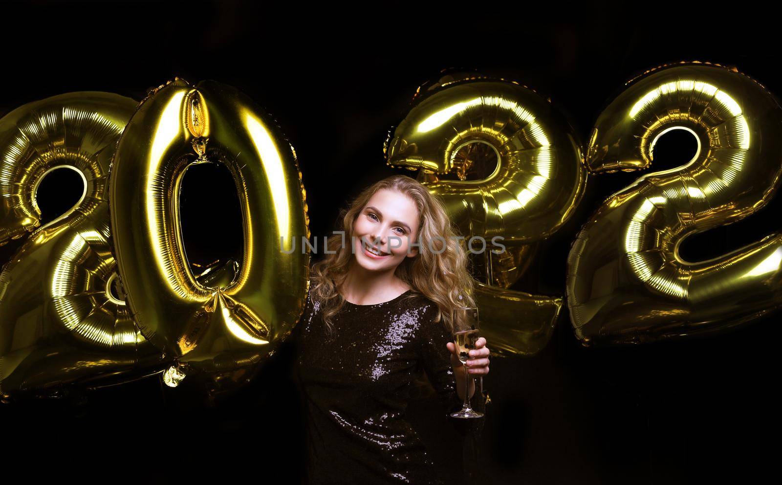 Happy gorgeous girl in stylish sexy party dress holding gold 2022 balloons, having fun at Christmas or New Year's Eve Party