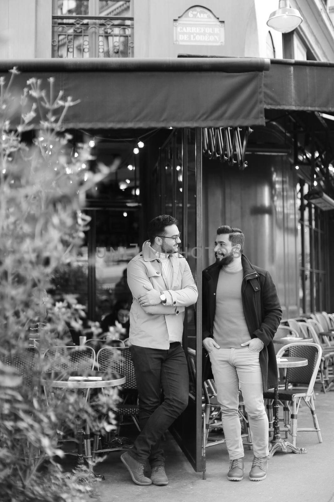 Black and white photo of two caucasian men standing and talking at street cafe. Concept of friendship and friends meeting.