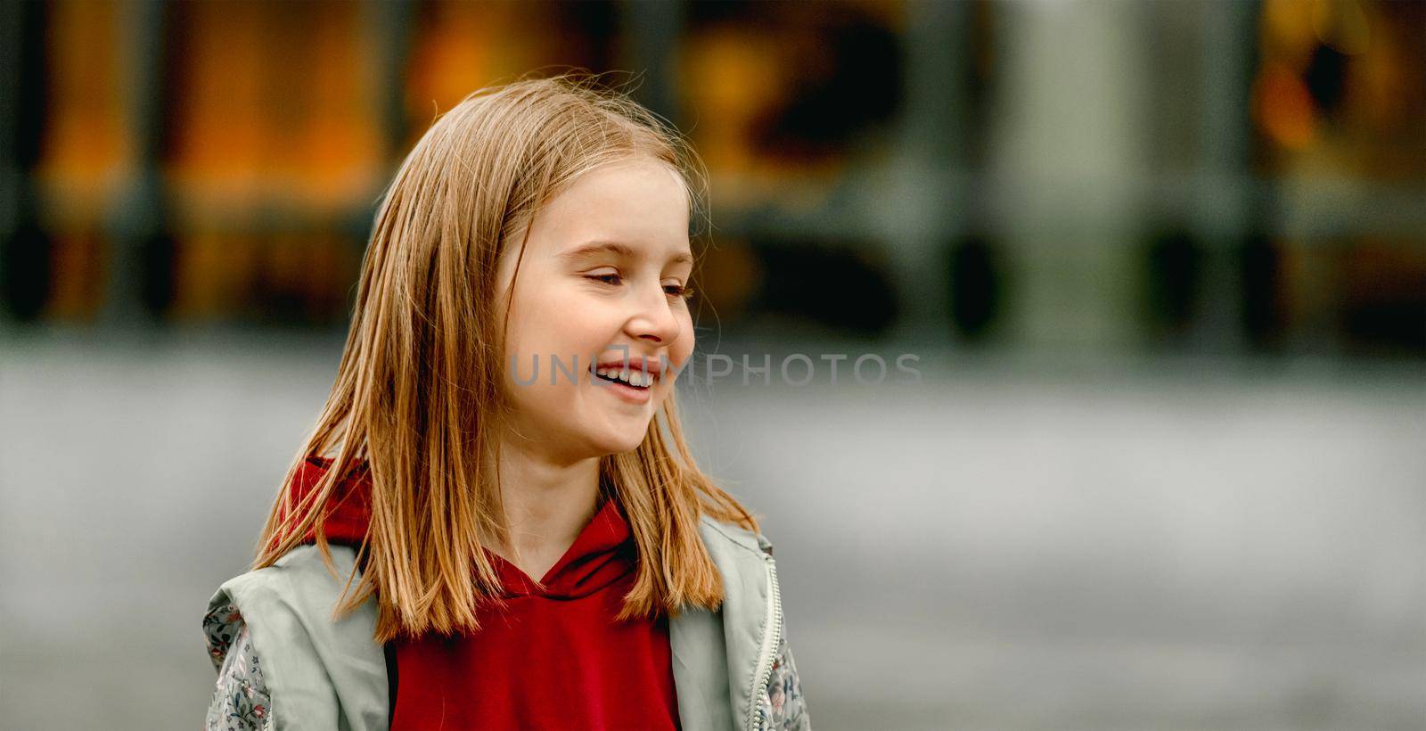 Pretty girl kid autumn portrait outdoors. Beautiful female child looking back and smiling