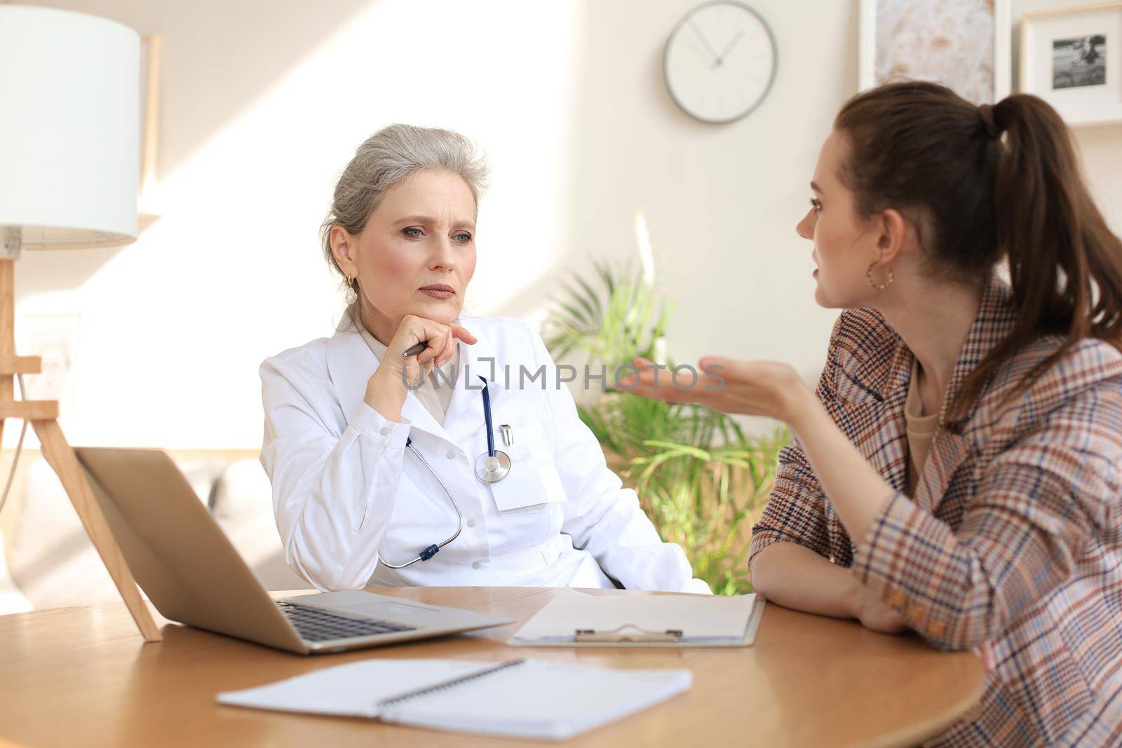 Middle aged female doctor therapist in consultation with patient in office
