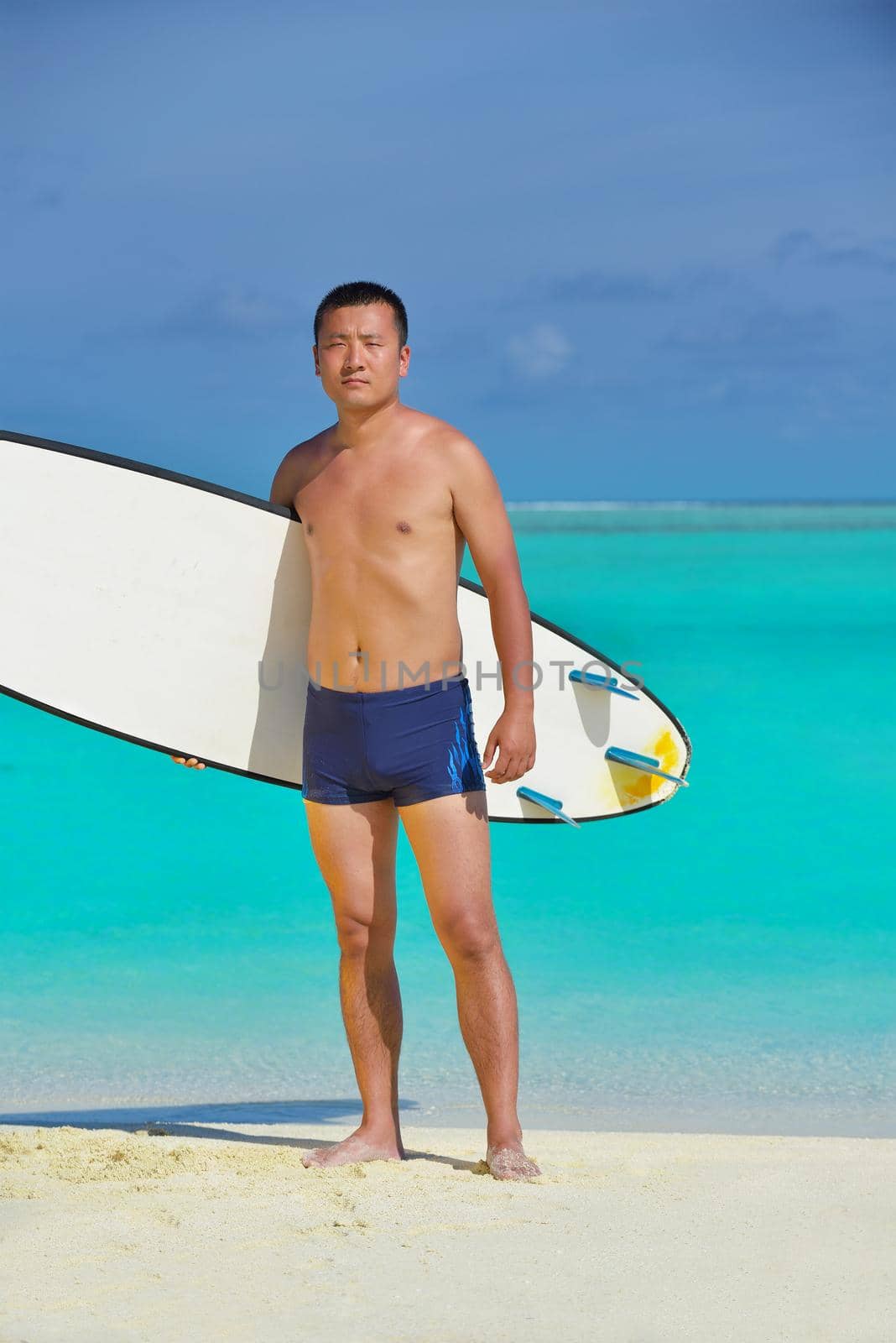 Man with surf board on beach by dotshock