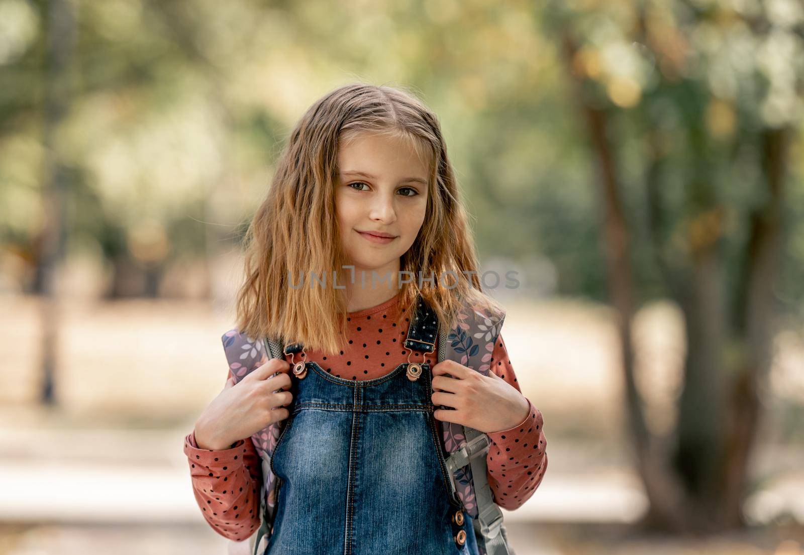Preteen school girl with backpack closeup portrait outdoors. Pretty pupil female kid after education class in autumn park