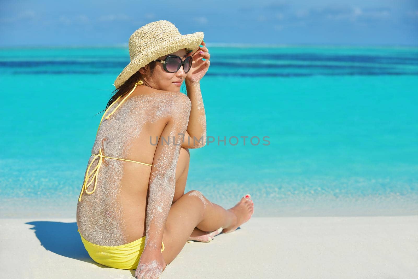 happy young beautiful asian woman resting on sand at tropical beach