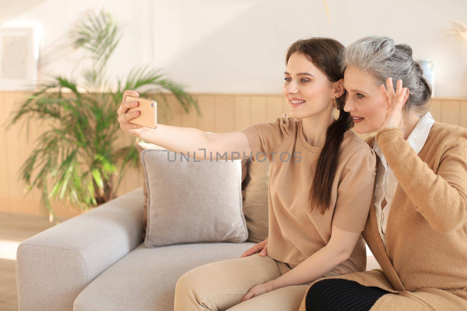 Happy middle aged mother and daughter taking selfie at home