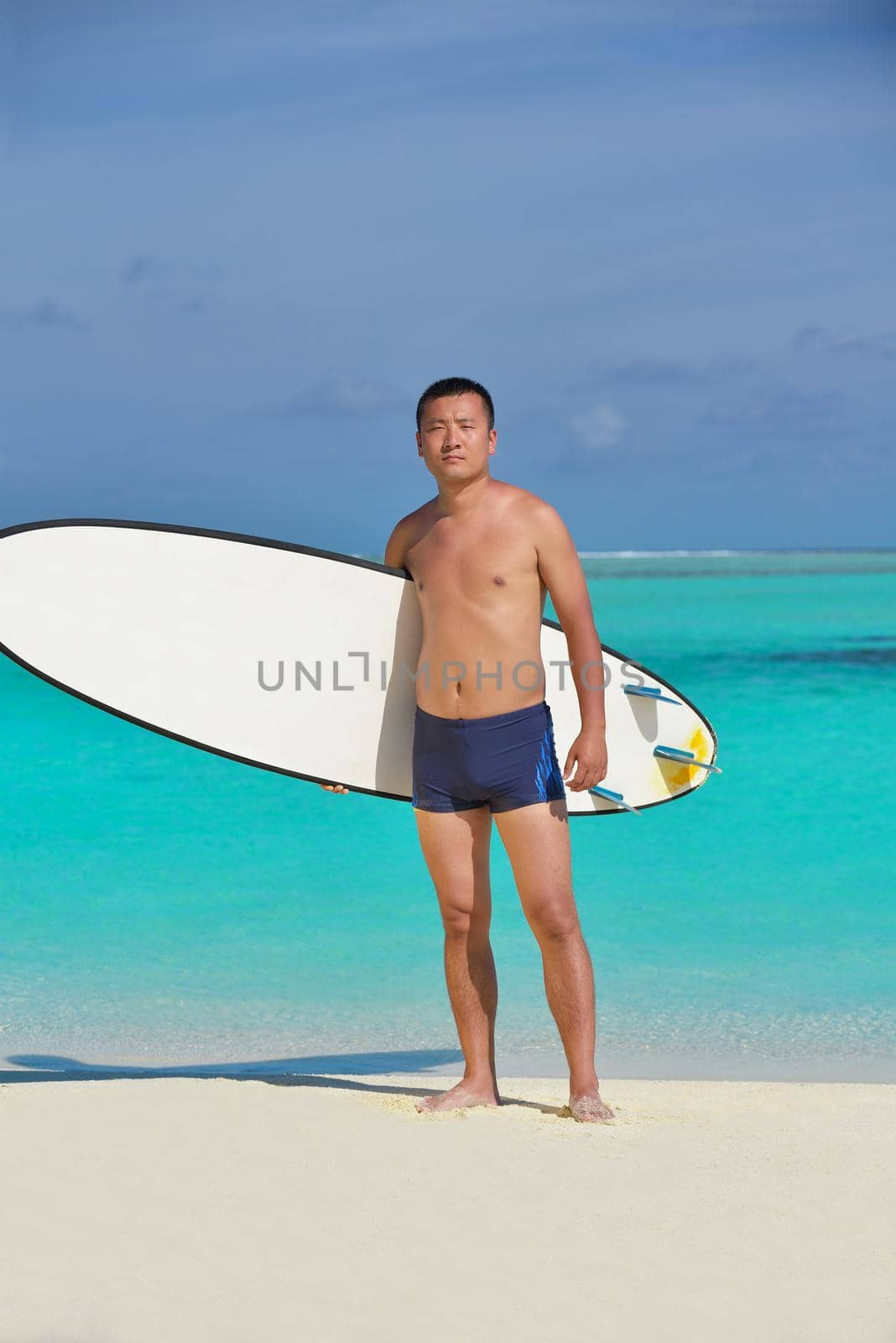 Man with surf board on beach by dotshock