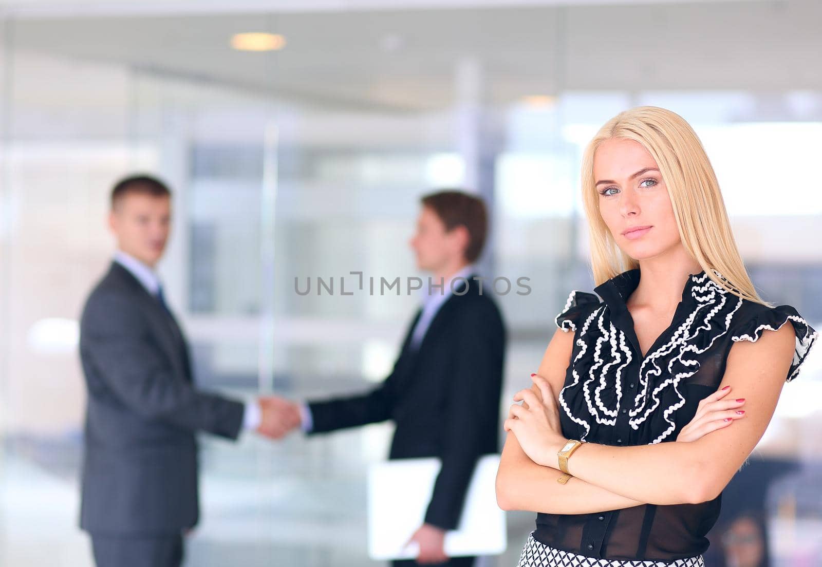 Business woman standing in foreground with a tablet in her hands