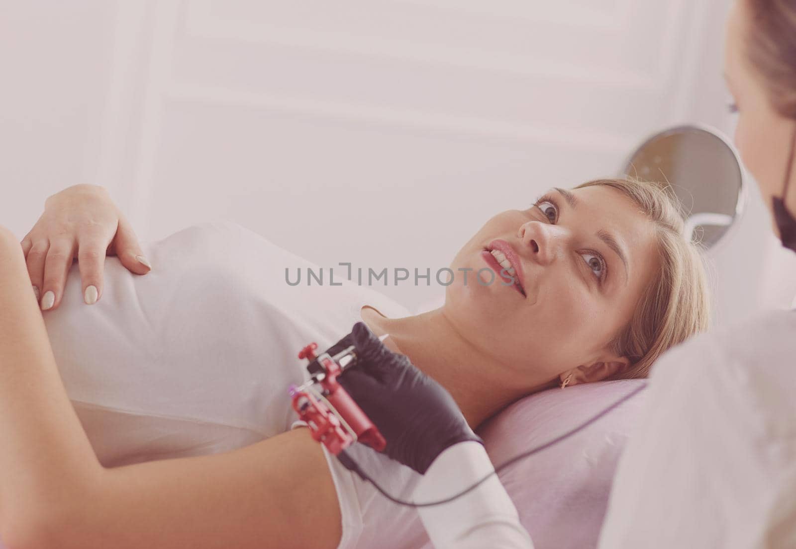 Young woman undergoing procedure of eyebrow permanent makeup in beauty salon.