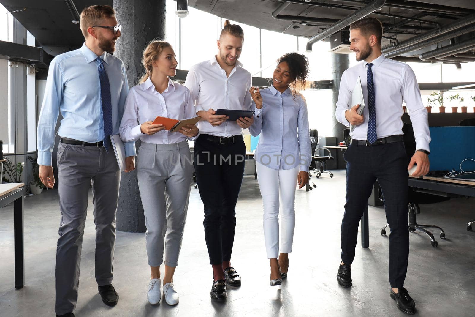 Modern business people discussing business and smiling while walking through the office corridor.