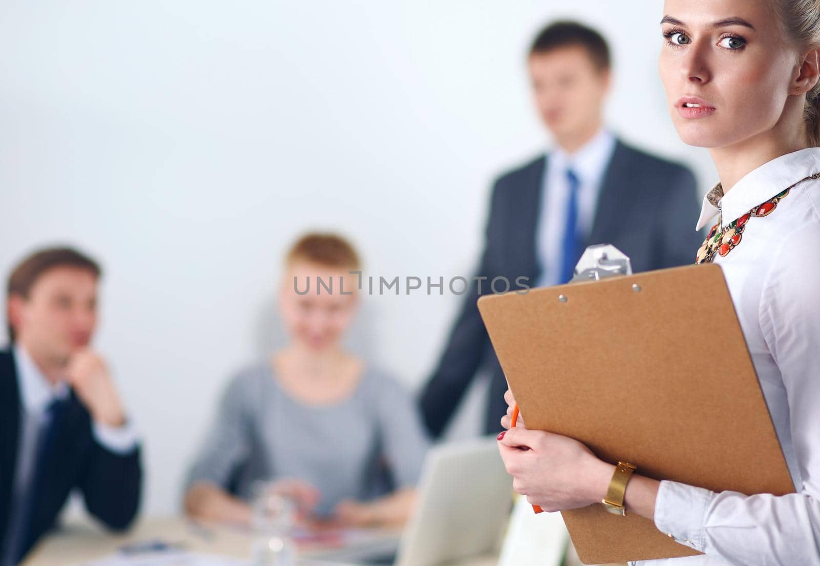 Portrait of a young woman working at office standing with folder .