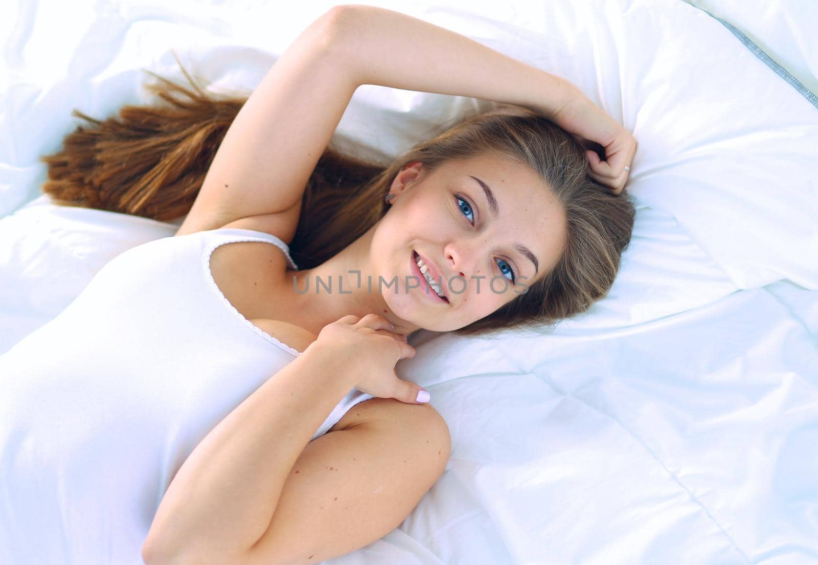 A beautiful young woman lying in bed comfortably and blissfully.