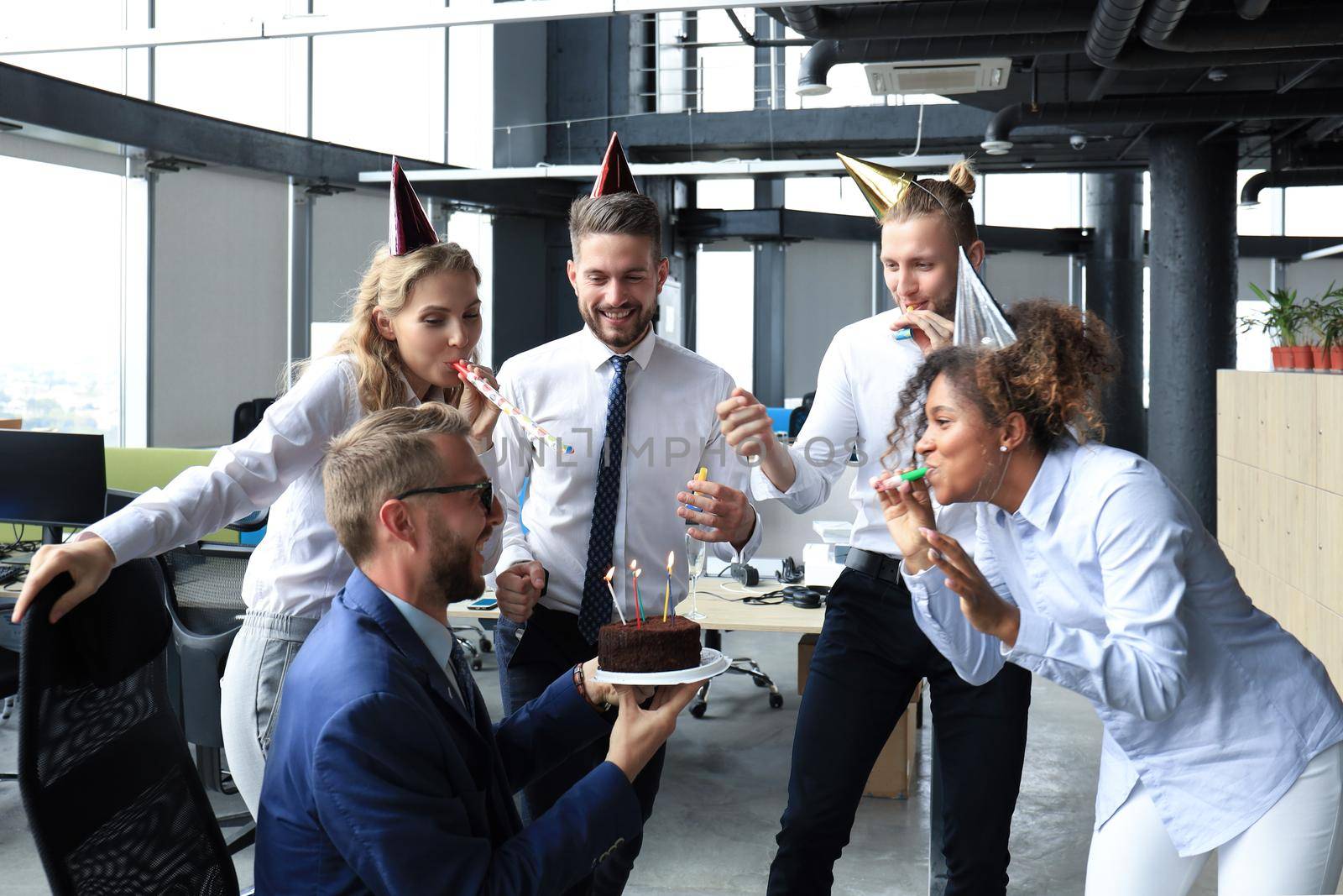 Happy business team with birthday cake are greeting colleague at office party.