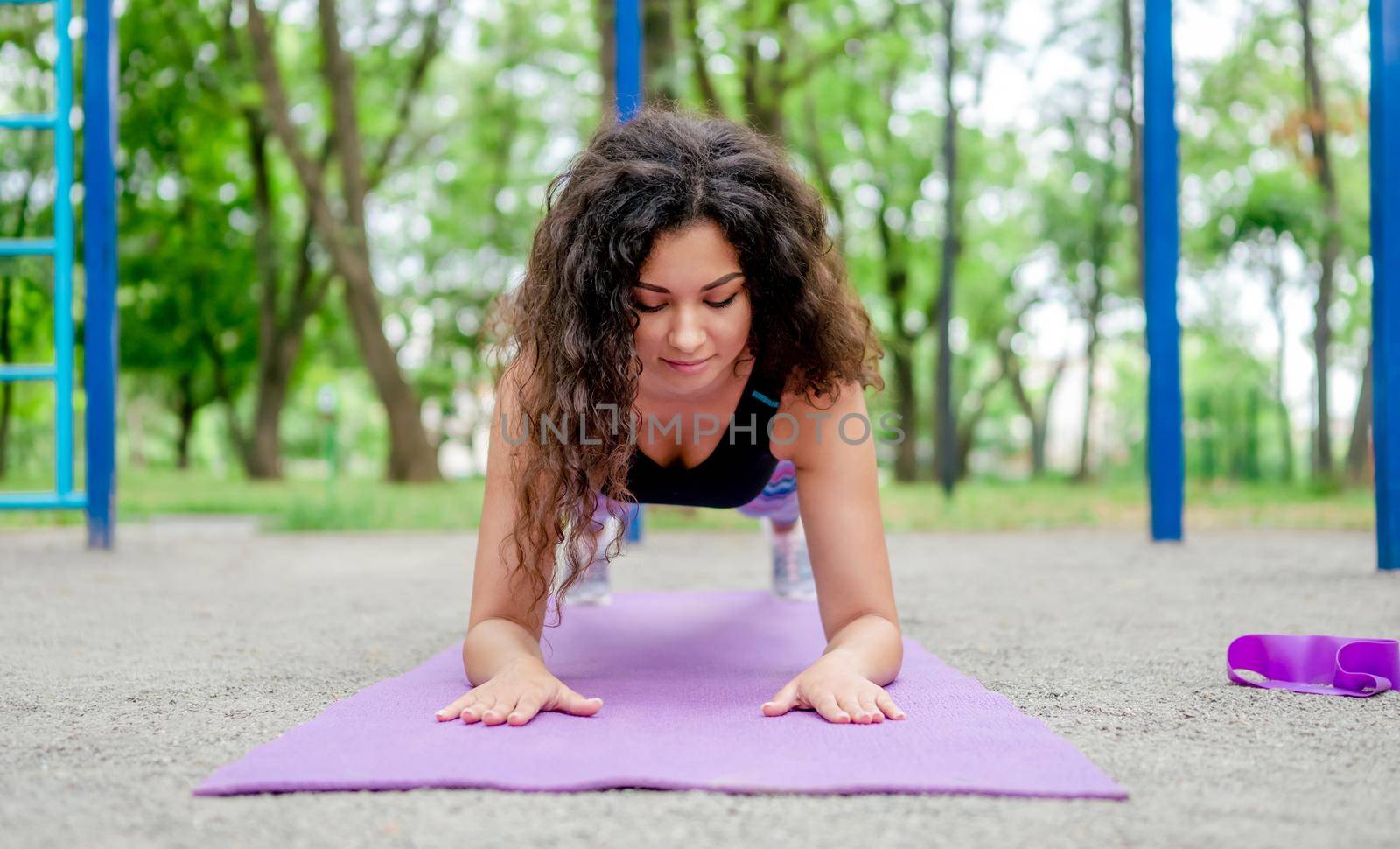 Sport girl doing plank exercise outdoors at summer. Young woman during workout at stadium