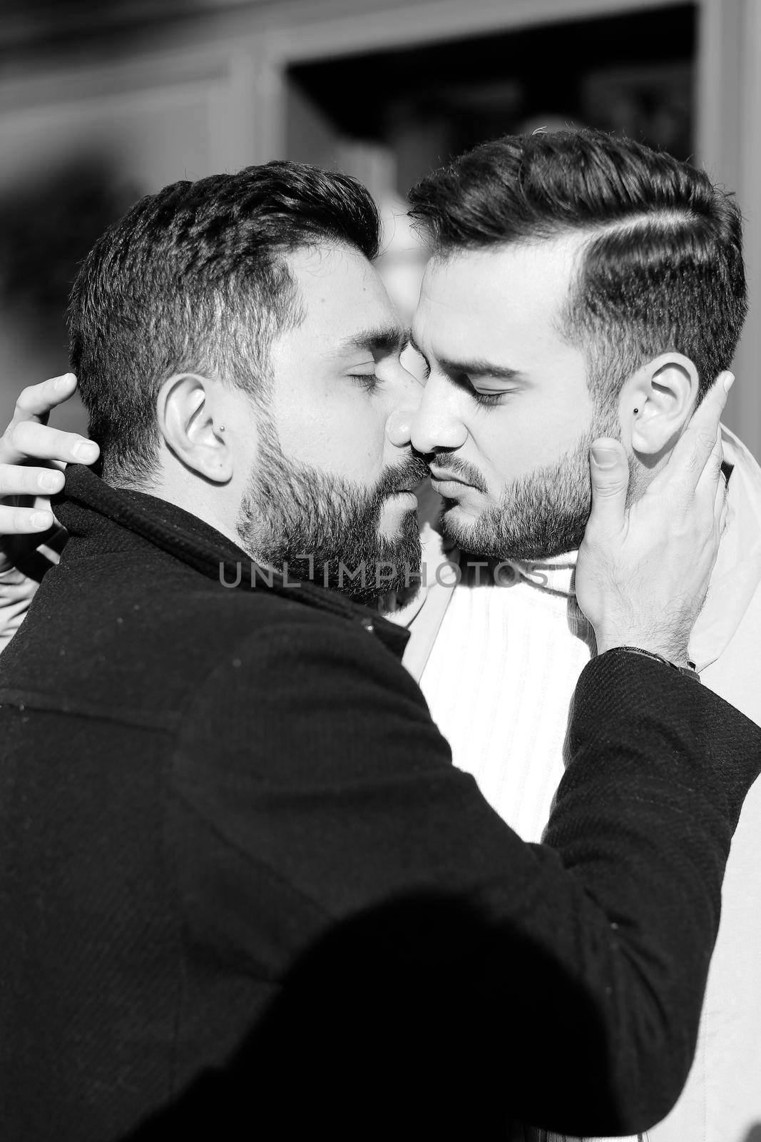 Black and white portrait of young american hugging and kissing gays. Concept of love, same sex couple and lgbt.