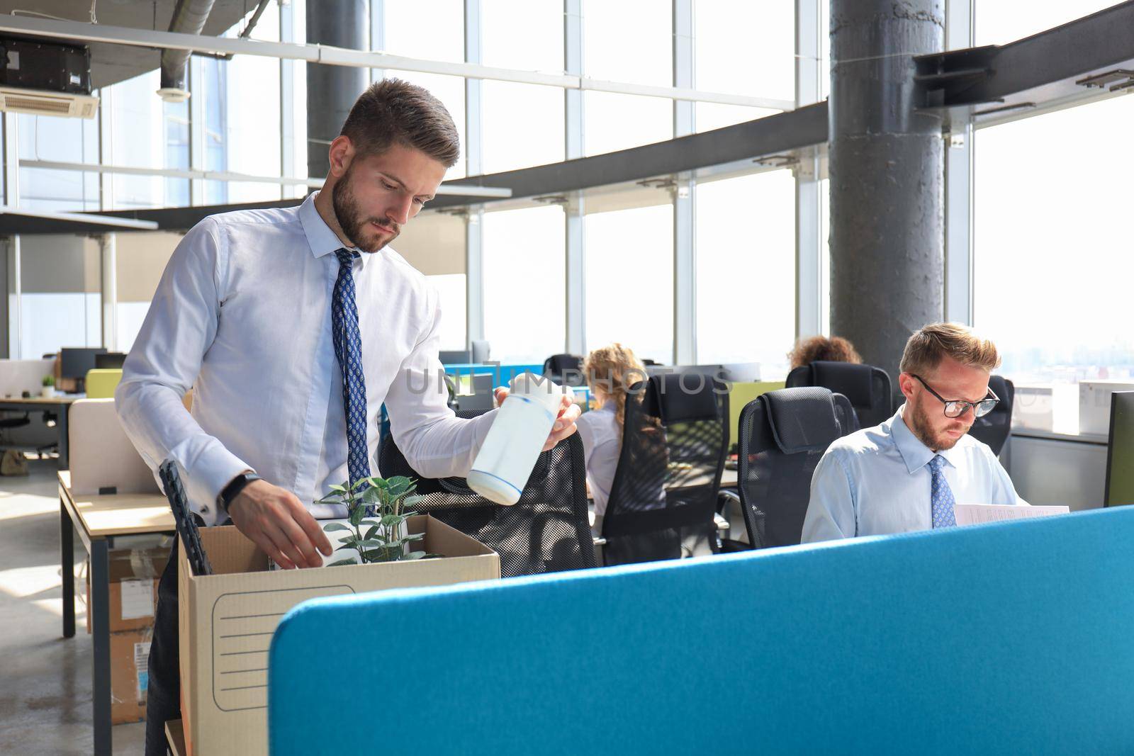 Sad dismissed worker are taking his office supplies with him from office.