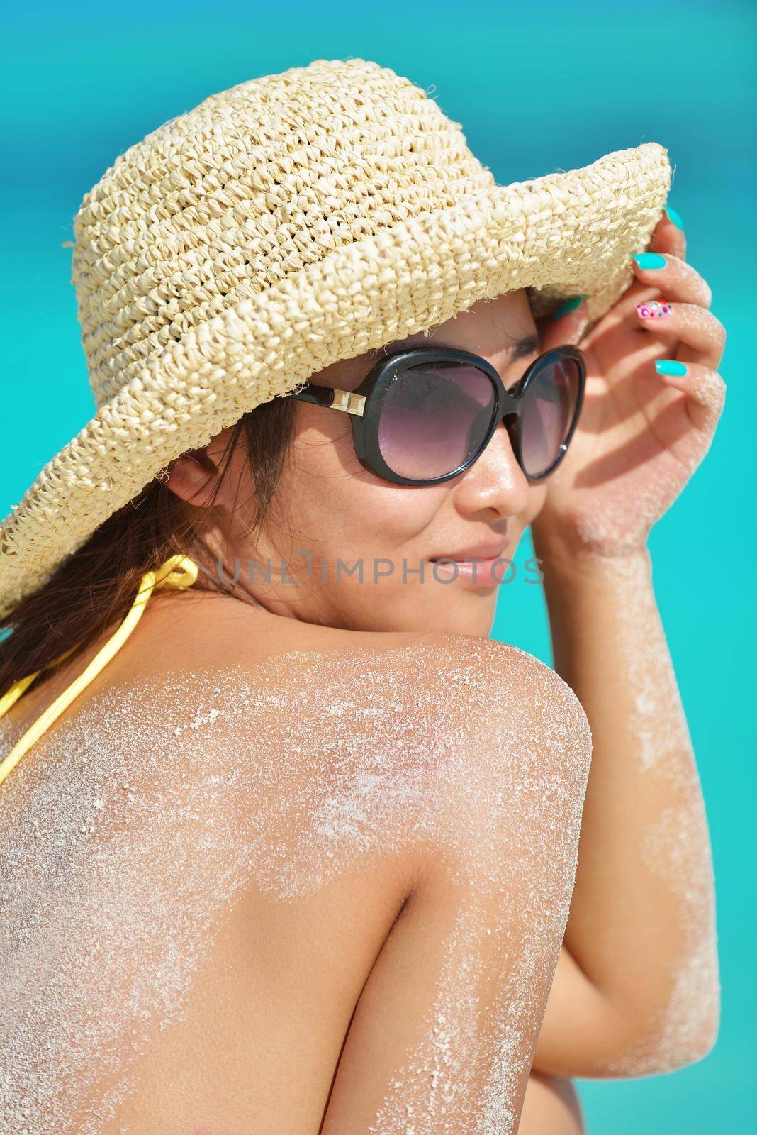 happy young pretty asian woman resting on sand at tropical beach