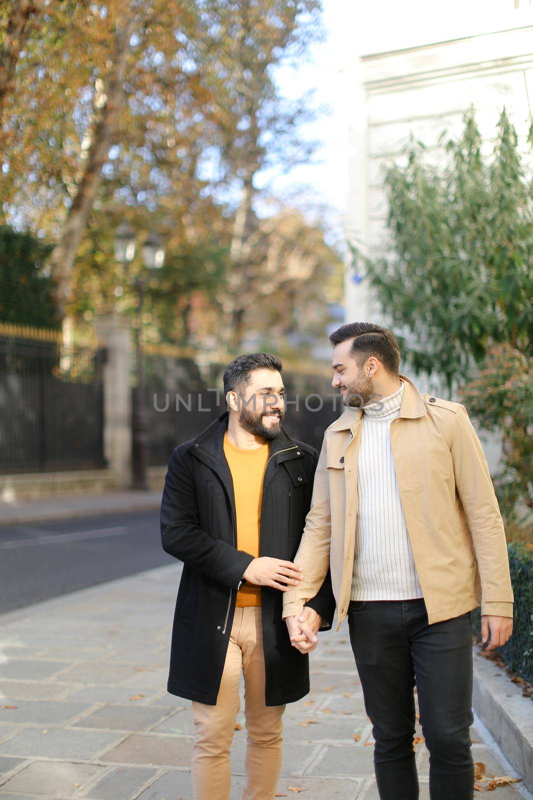 Happy gays walking and holding hands in city. Concept of same sex couple and lgbt.