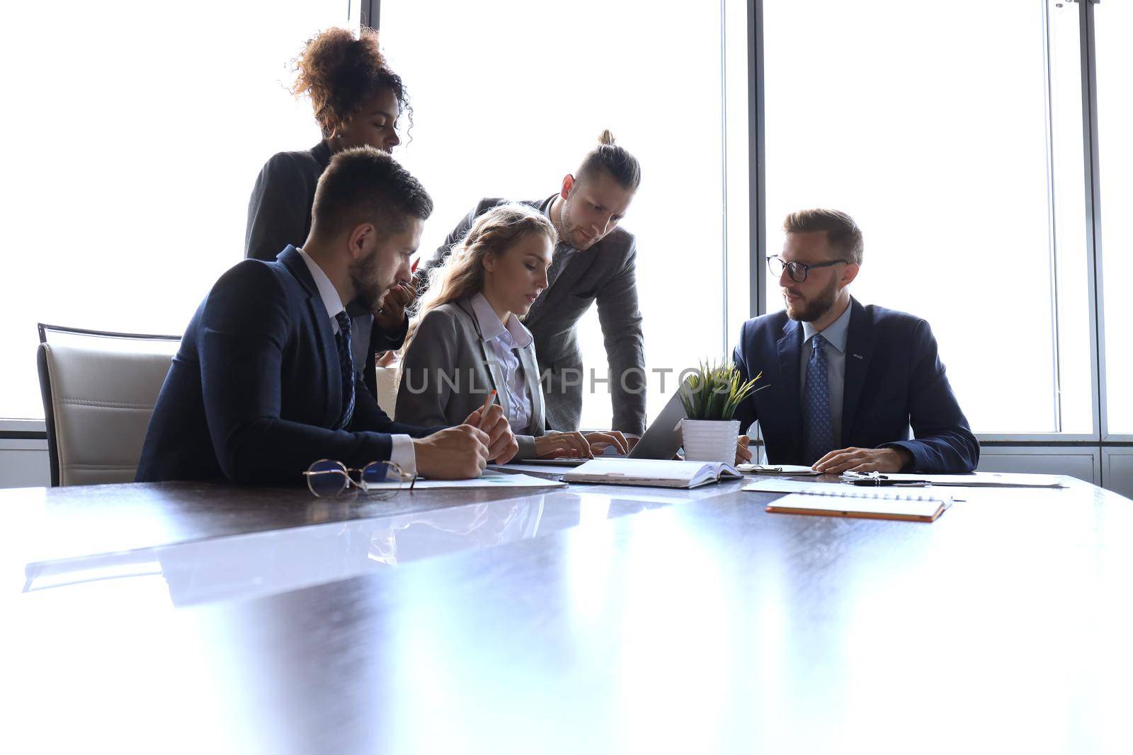 Group of young modern people in formalwear discussing something while working in the modern office.