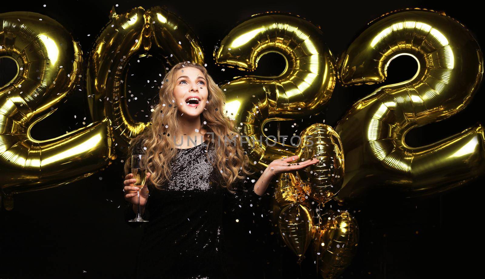 Happy gorgeous girl in stylish sexy party dress holding gold 2022 balloons, having fun at Christmas or New Year's Eve Party