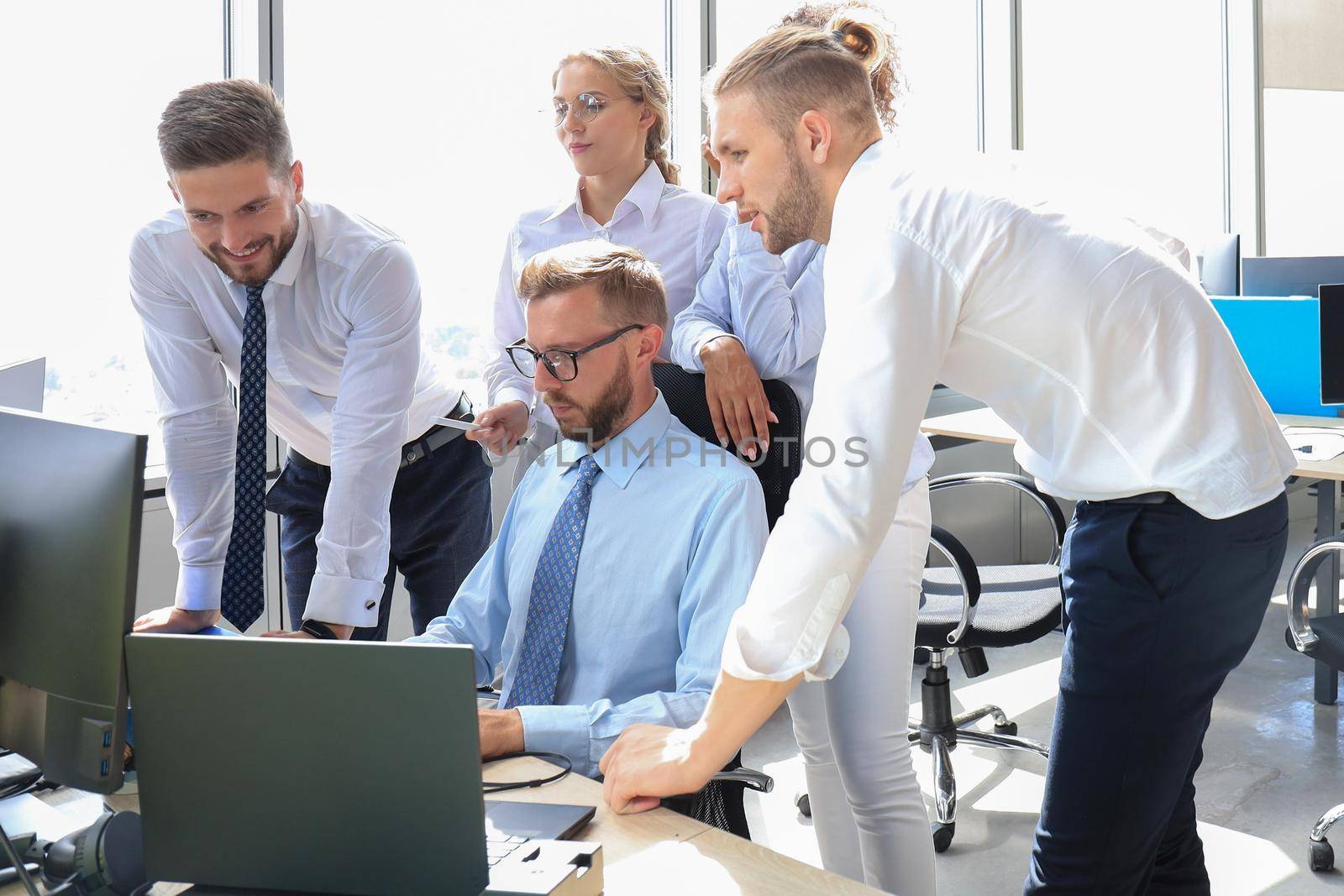 Group of young modern people in formalwear using modern technologies while working in the creative office.