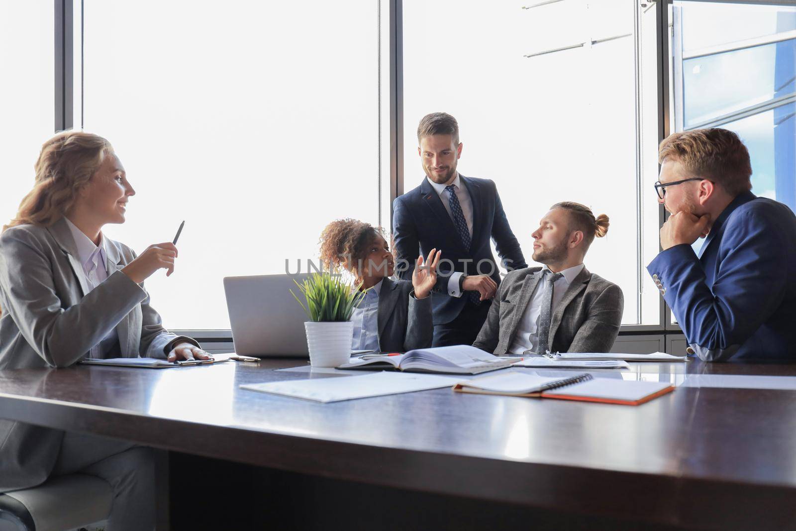 Group of young modern people in formalwear smiling and discussing something while working in the modern office.