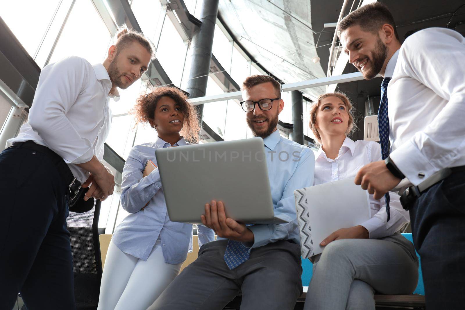 Group of modern business people working together in creative office while standing near the desk.