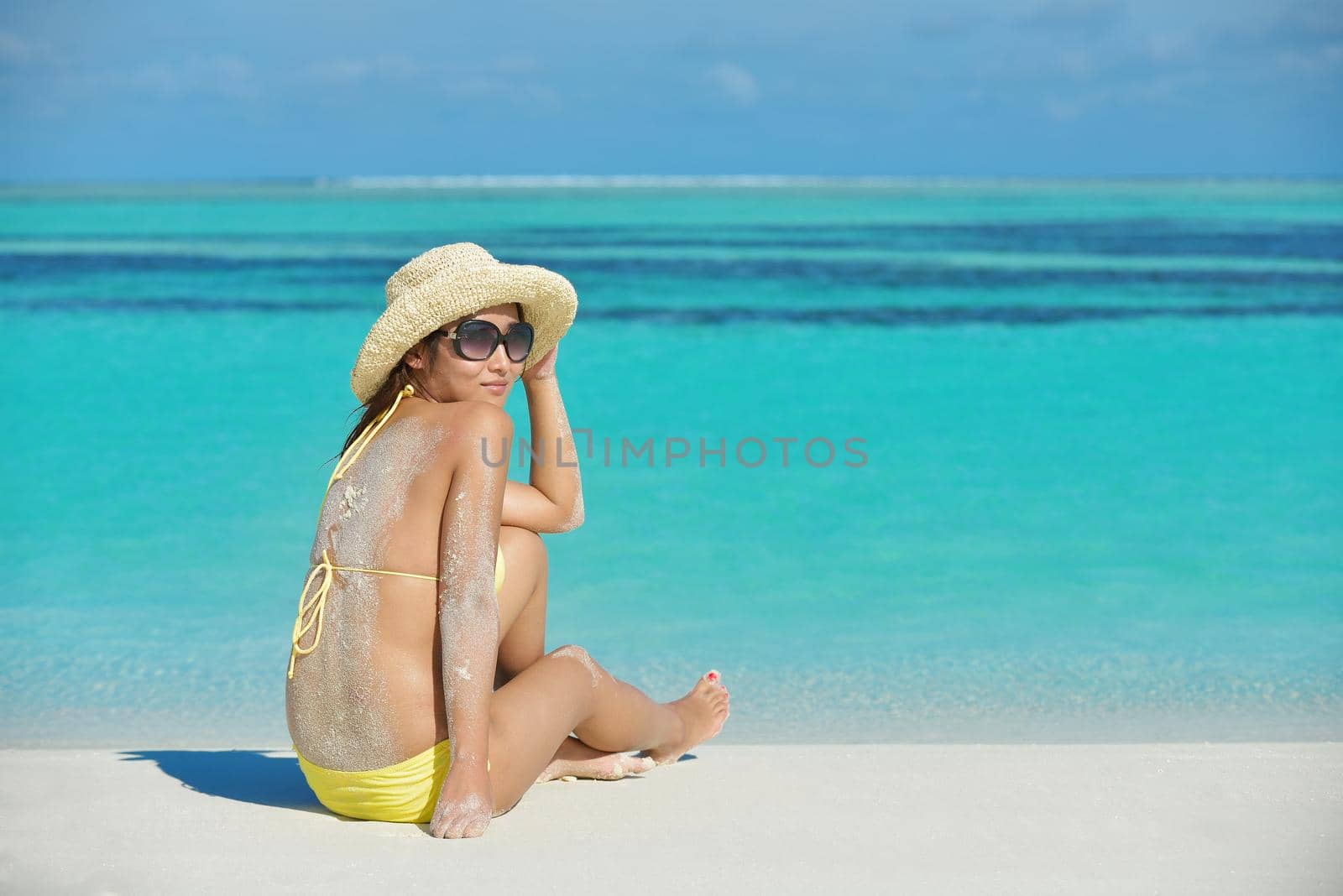 happy young pretty asian woman resting on sand at beach