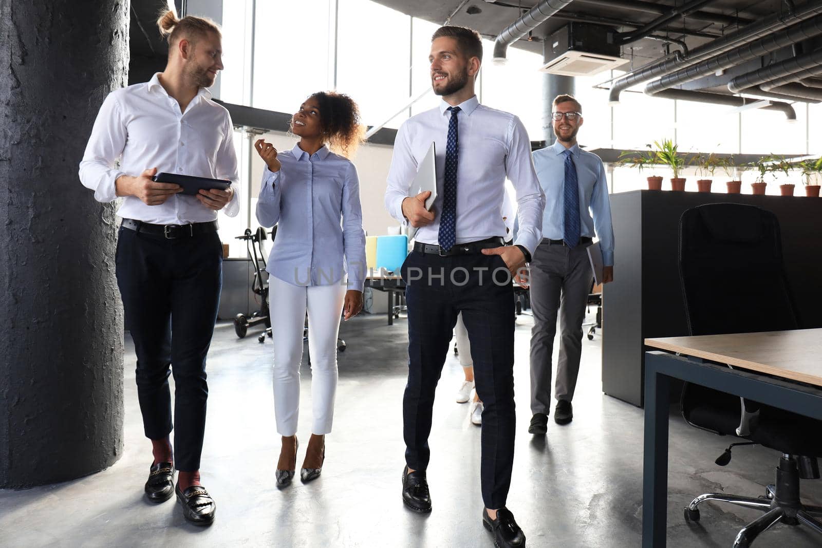 Modern business people discussing business and smiling while walking through the office corridor.