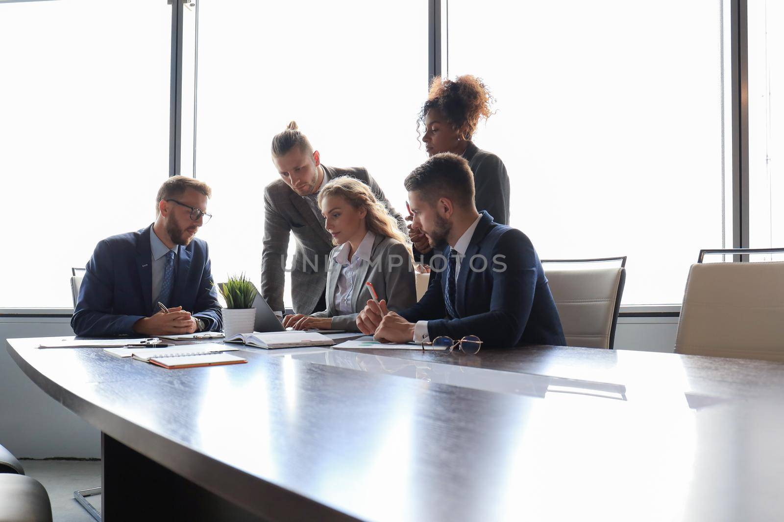 Group of young modern people in formalwear smiling and discussing something while working in the modern office.