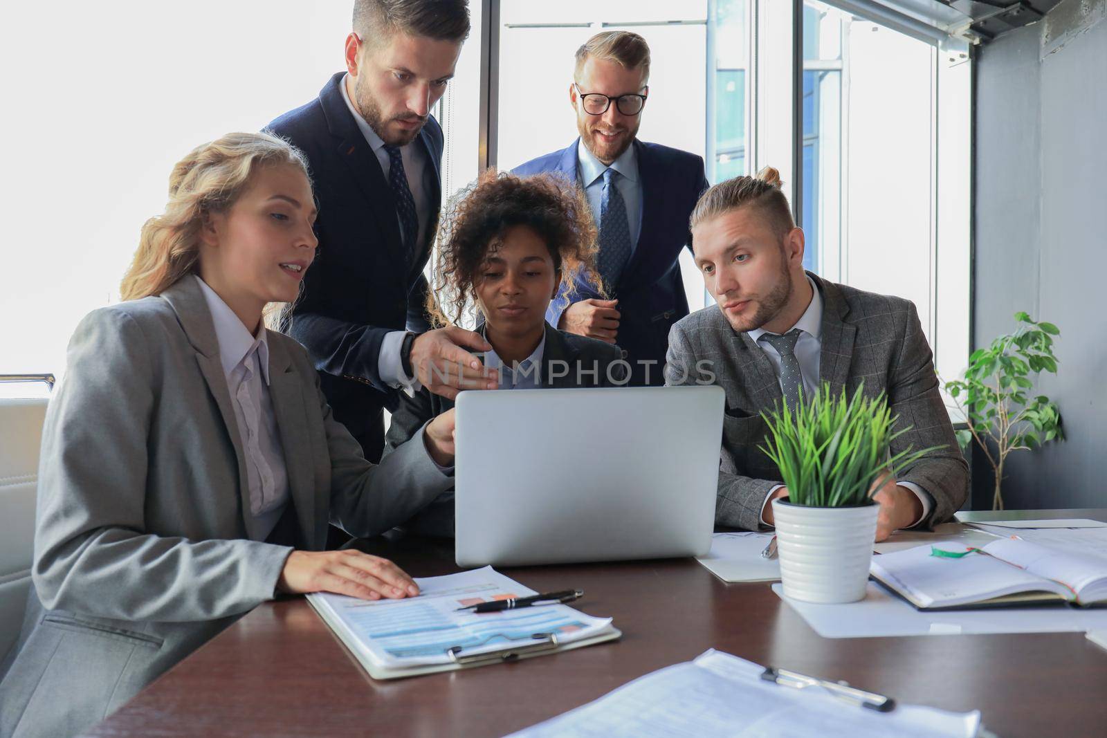 Group of young modern people in formalwear smiling and discussing something while working in the modern office.