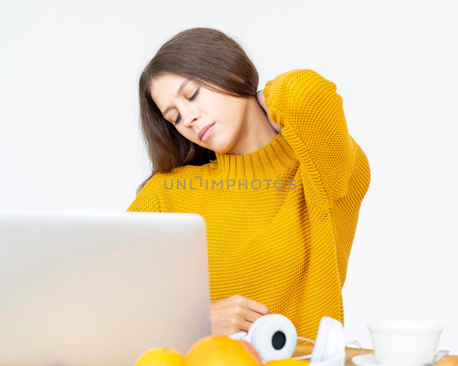 Woman massaging neck pain from working at computer for long time by NataBene