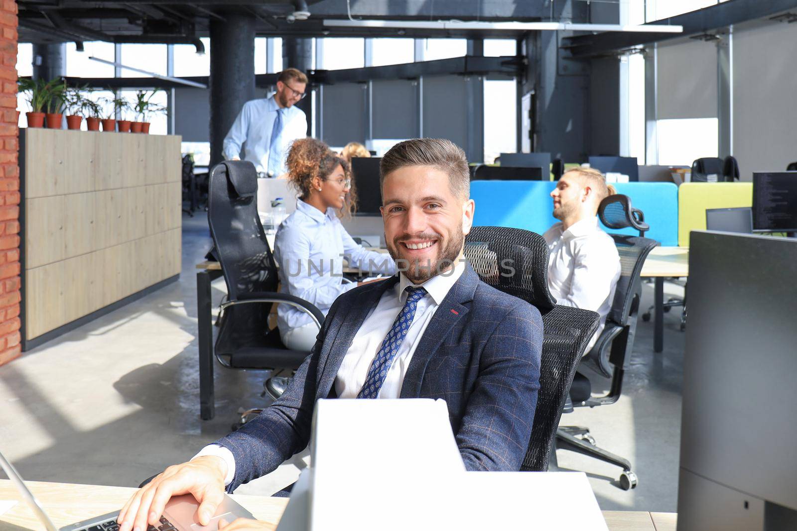 Businessman with colleagues in the background in modern office.