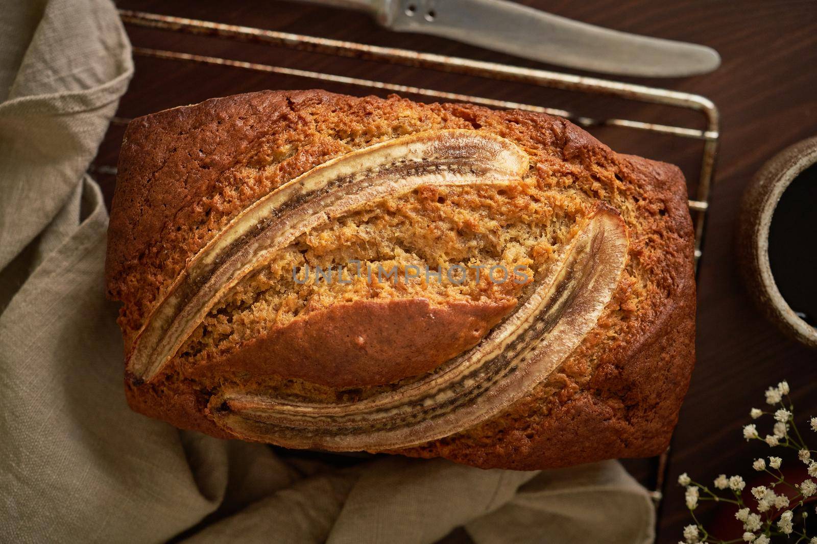 Banana bread. Cake with banana, traditional american cuisine. Whole loaf. Dark background, black table, shadows. Top view, close up.