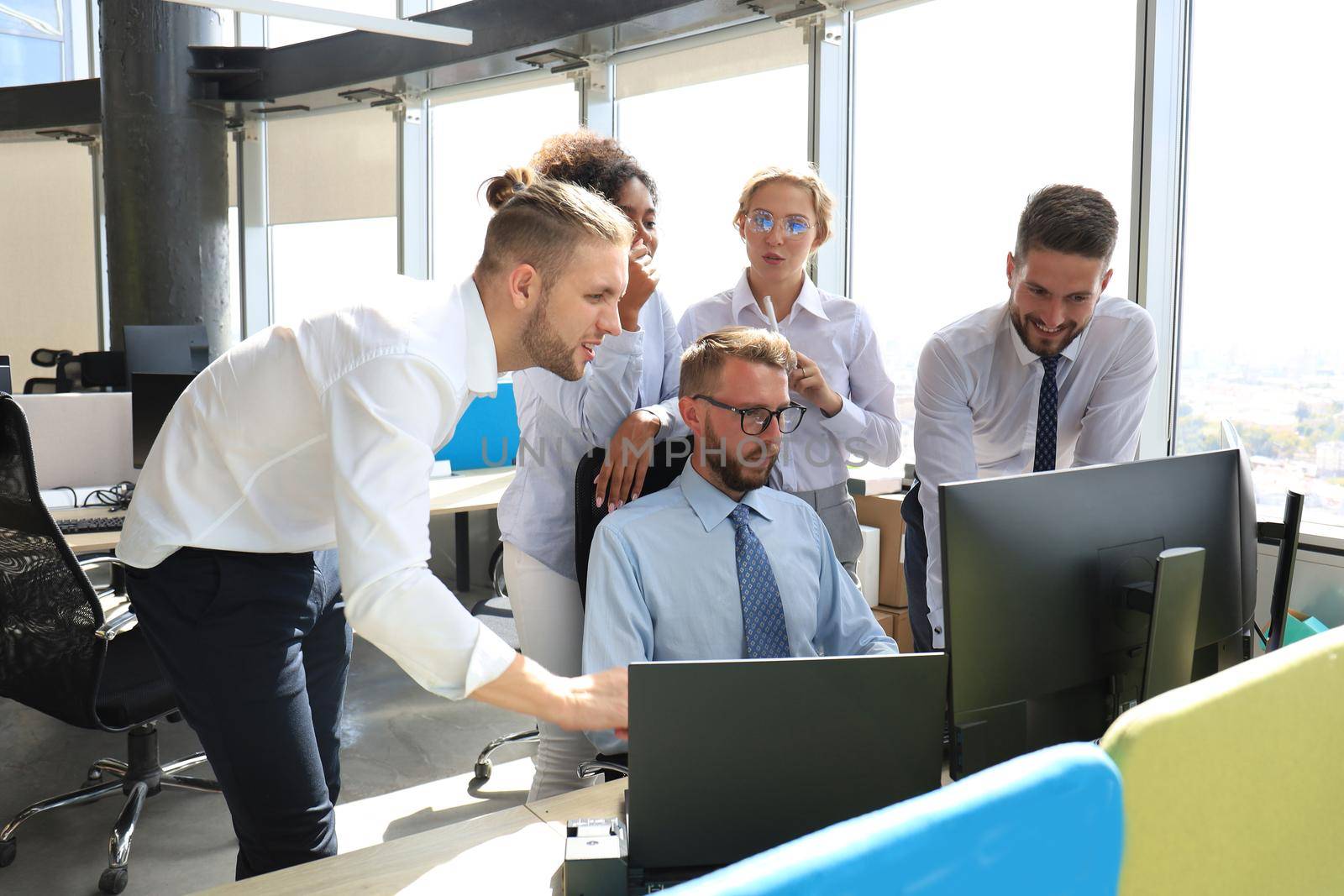 Group of young modern people in formalwear using modern technologies while working in the creative office.