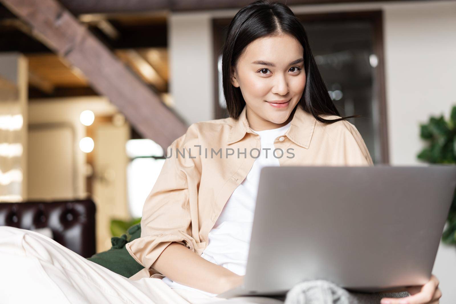 Asian girl using laptop computer from home, working or resting, watching videos on pc.