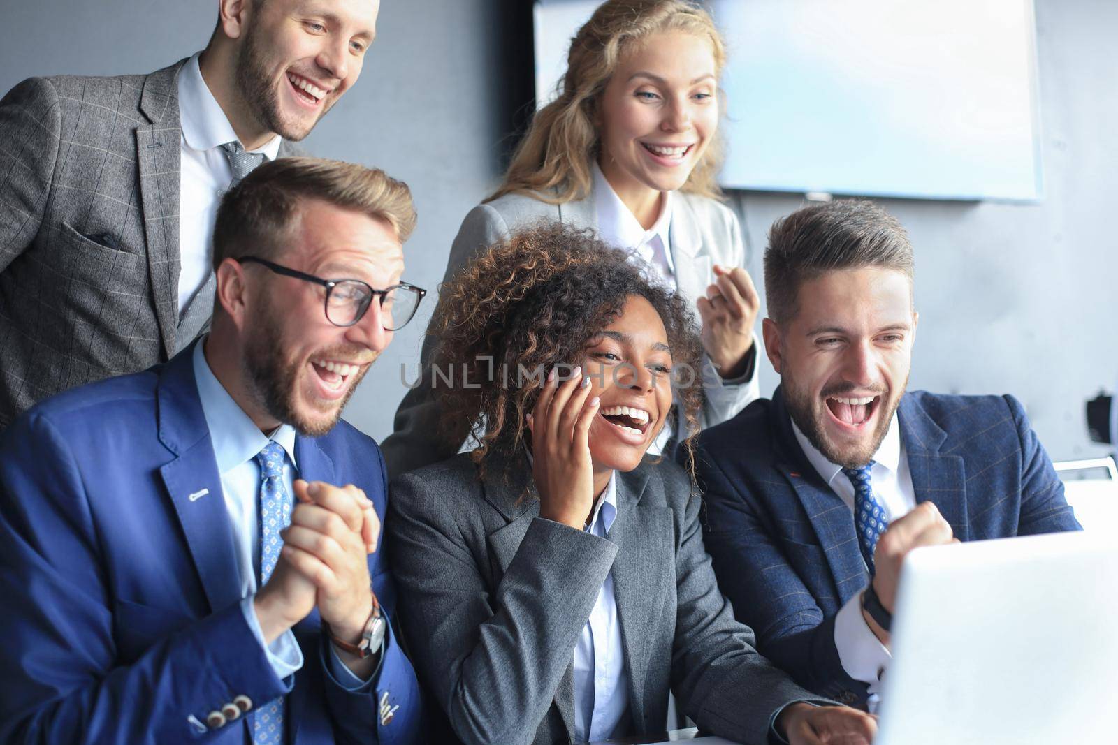 Happy business people laugh near laptop in the office. Successful team coworkers joke and have fun together at work