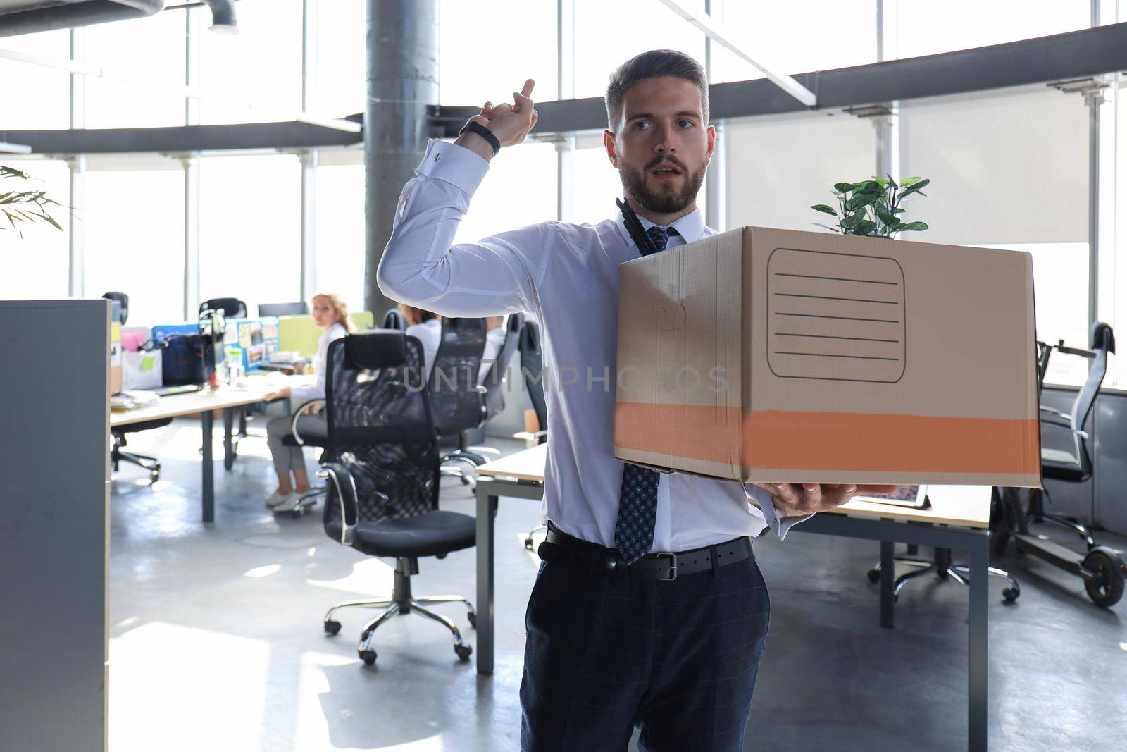Dismissed worker going from the office with his office supplies showing fuck.