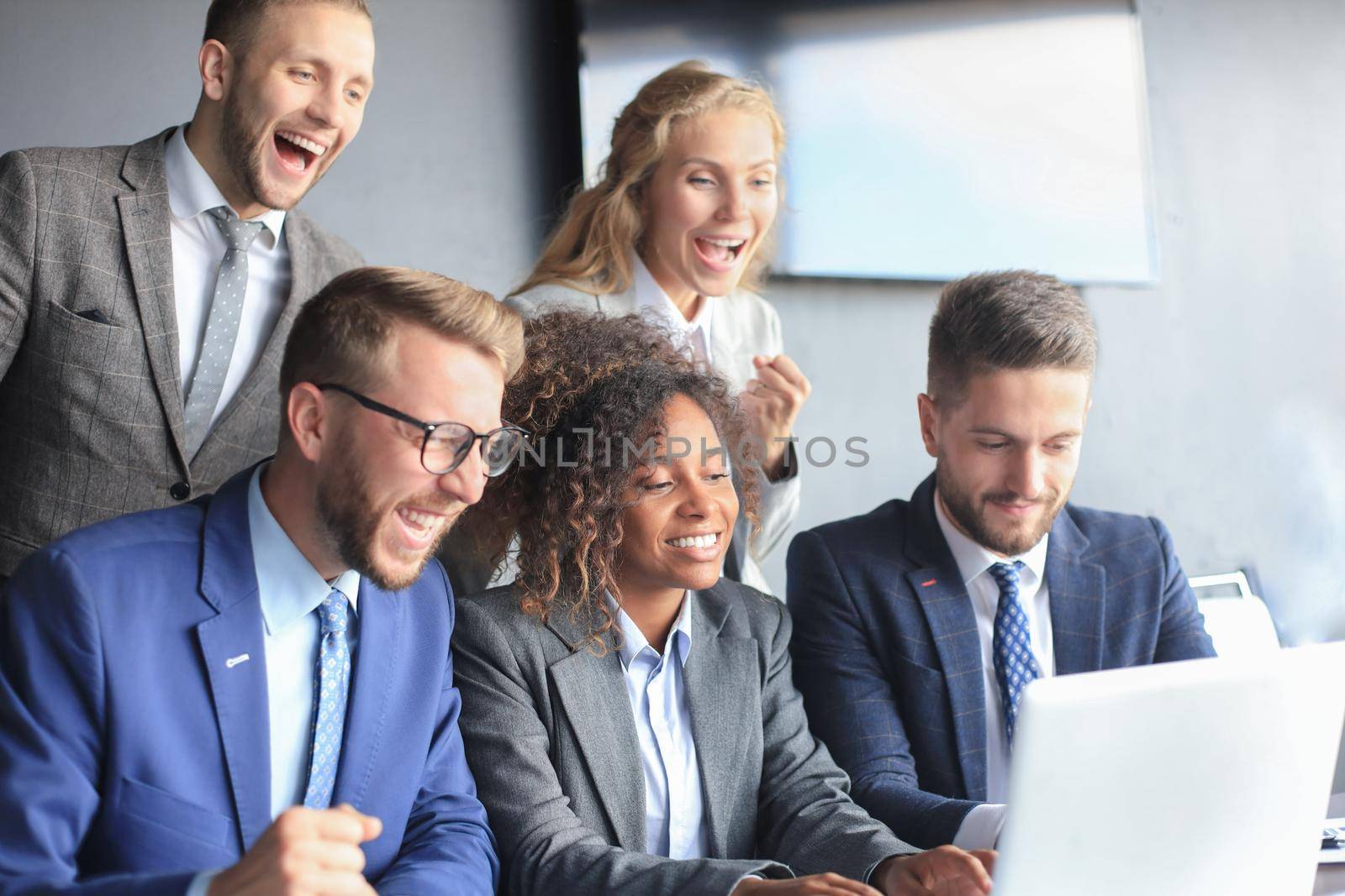 Happy business people laugh near laptop in the office. Successful team coworkers joke and have fun together at work