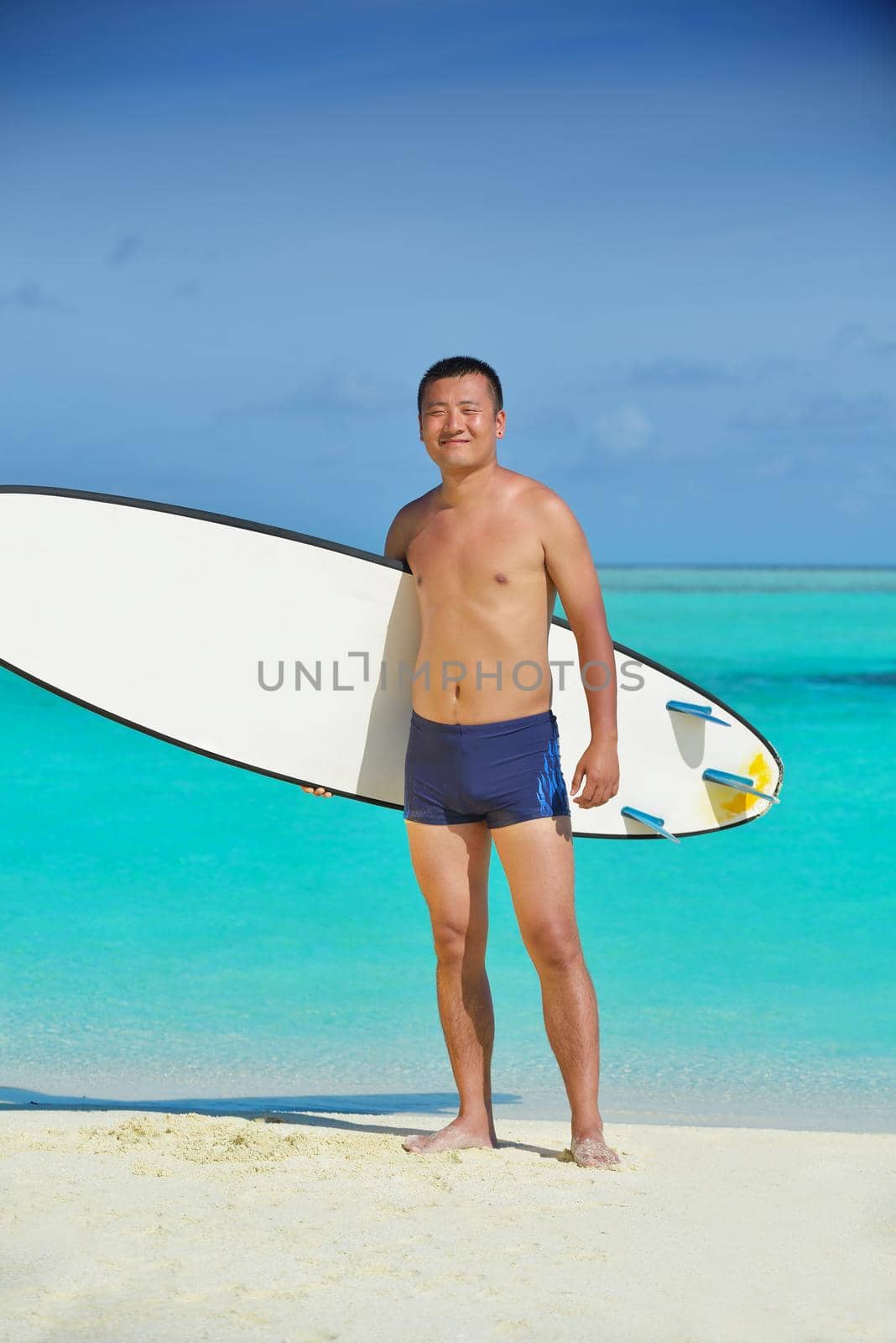 Man with surf board on beach by dotshock