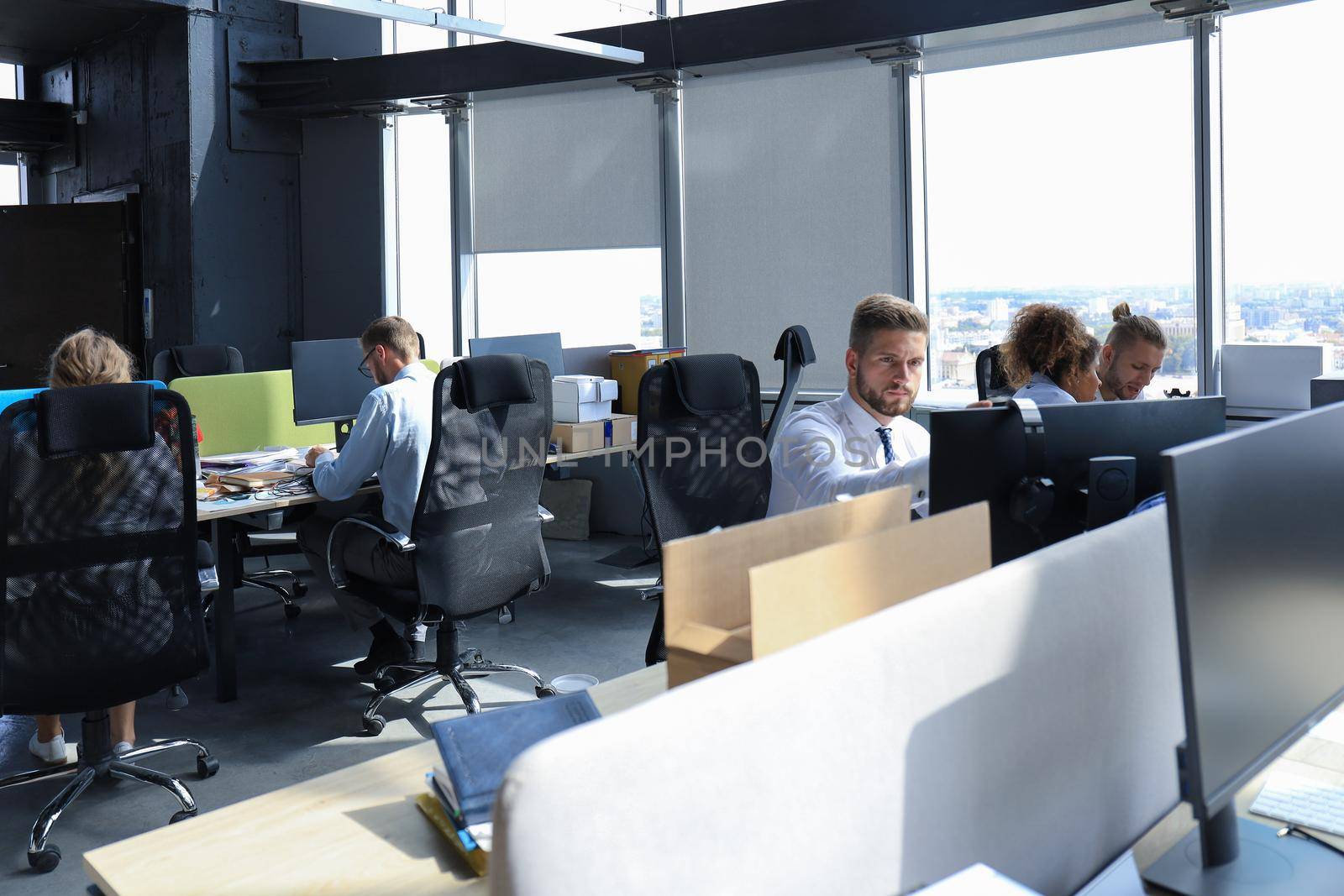 Group of young modern people in formalwear using modern technologies while working in the creative office.